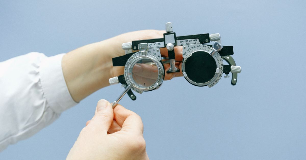 Des mains ajustant un ensemble de lentilles d'essai en optométrie avec un fond bleu. Idéal pour les sujets de vision et de santé.