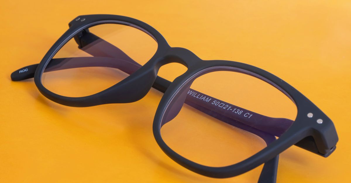 Lunettes noires modernes présentées sur un fond orange vif avec une marque visible.